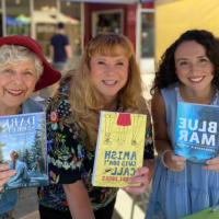 Francesca Varela and two other local authors smiling and holding their books.