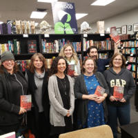 Francesca Varela standing with a group of people in front of bookshelves at a book store in Gresham, Oregon.