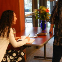 Francesca Varela sitting at a table signing books.